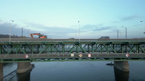 cars on the bridge overtake a slow-moving excavator