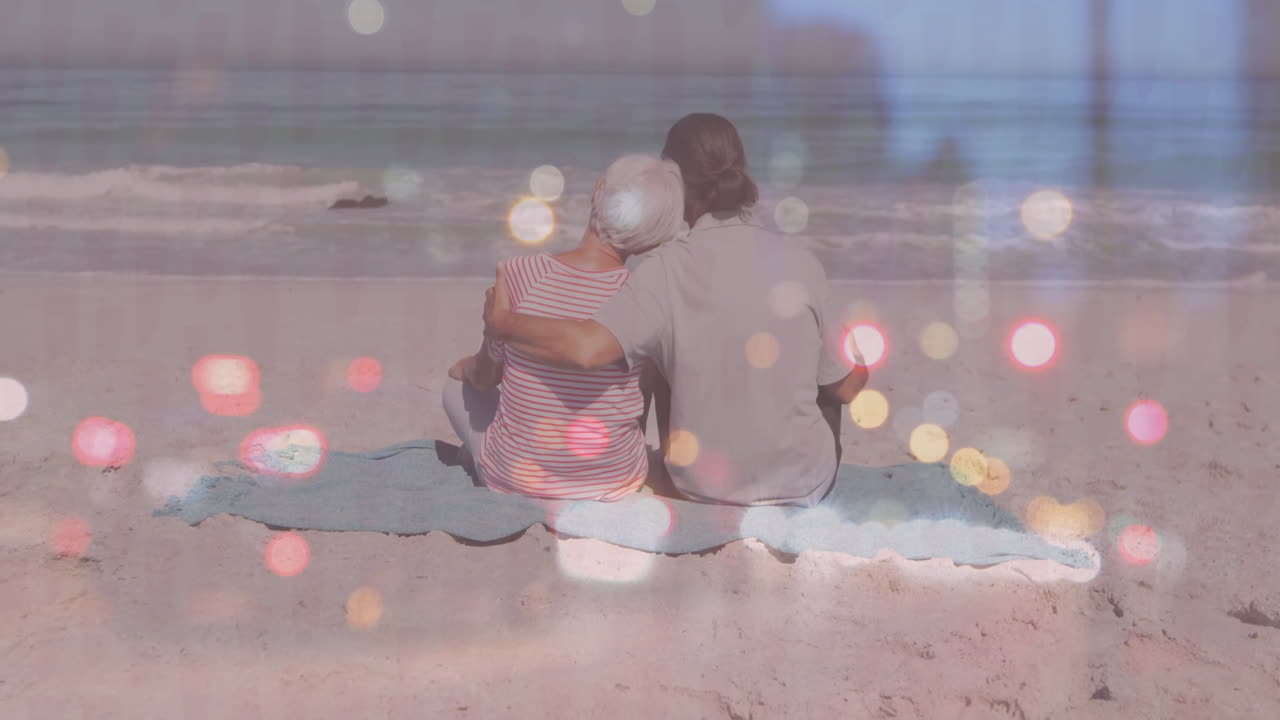 mother and son watching ocean waves on beach blanket, showing floating health icons
