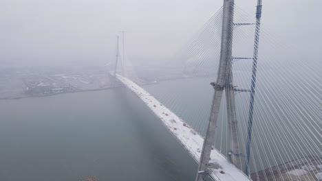 aerial view of gordie howe bridge disappearing into dense winter mist over detroit river