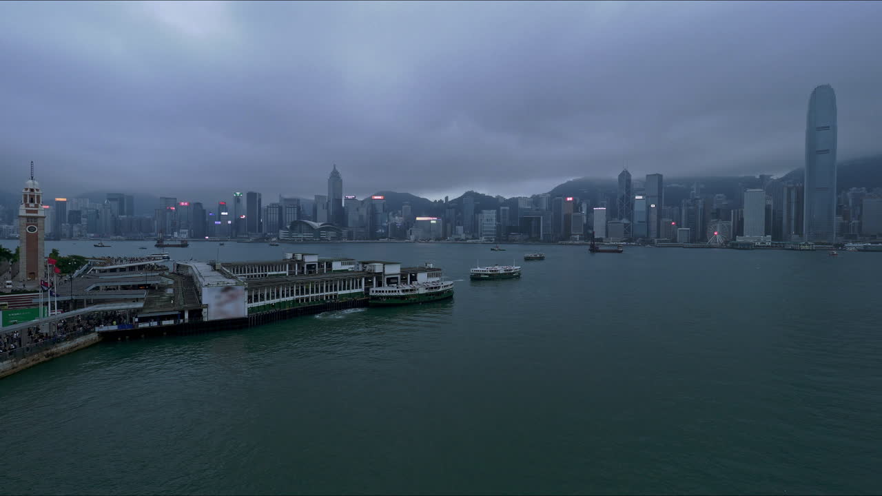 horizonte de la isla de hong kong visto desde el paseo marítimo de kowloon al atardecer bajo un cielo cambiante