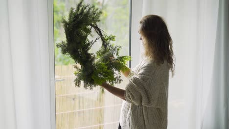 Woman making Christmas wreath in interior