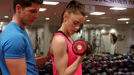 mujer levantando pesas con su entrenador