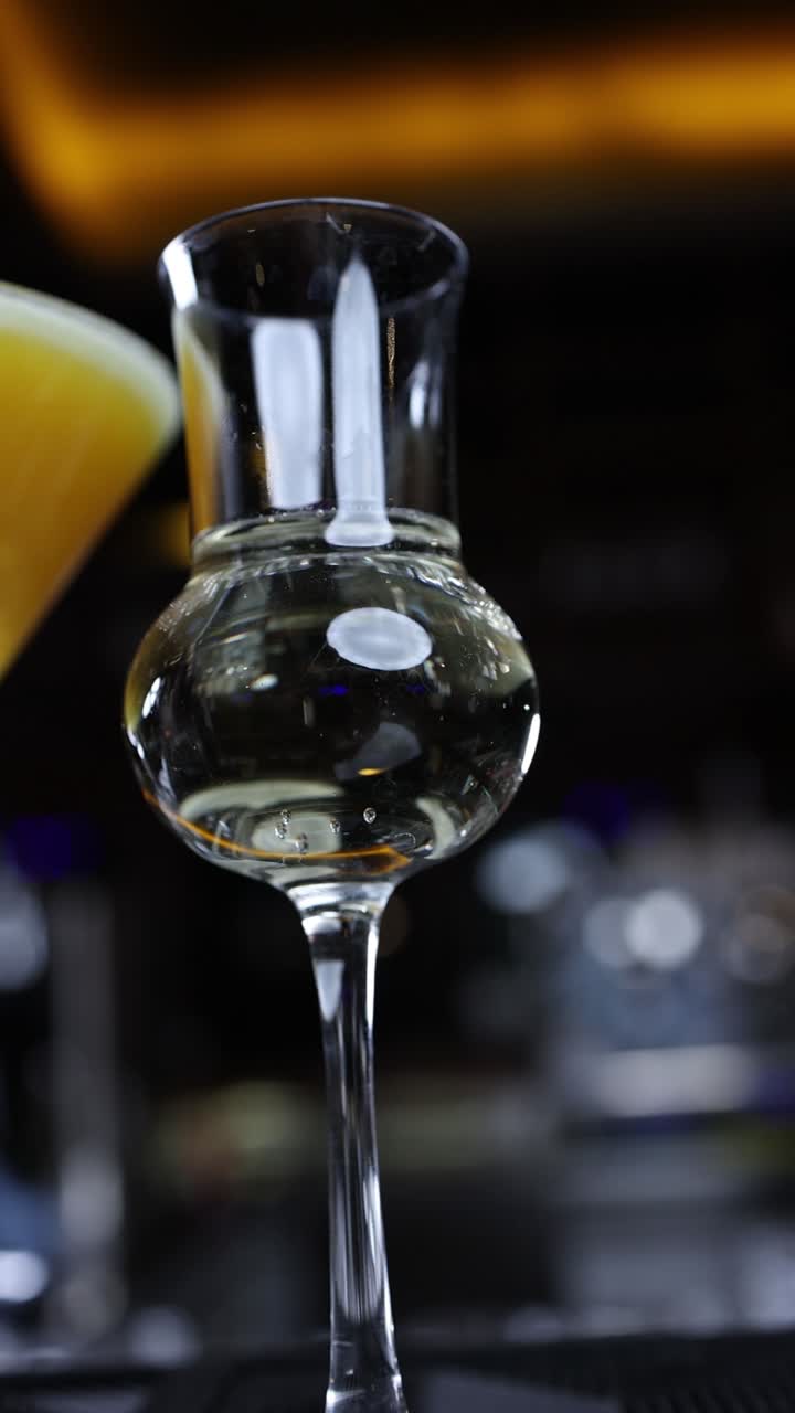 Primo piano di un bicchiere di liquore con cocktail sullo sfondo