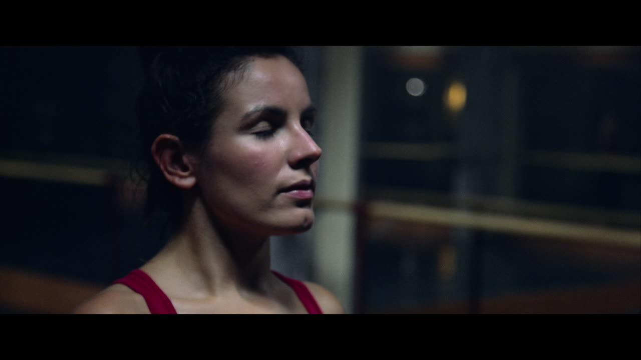A young woman practices modern dancing and ballet in a moody room full of mirrors