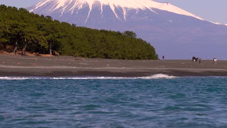 slow tilt up over beautiful beach and mount fuji with many tourists