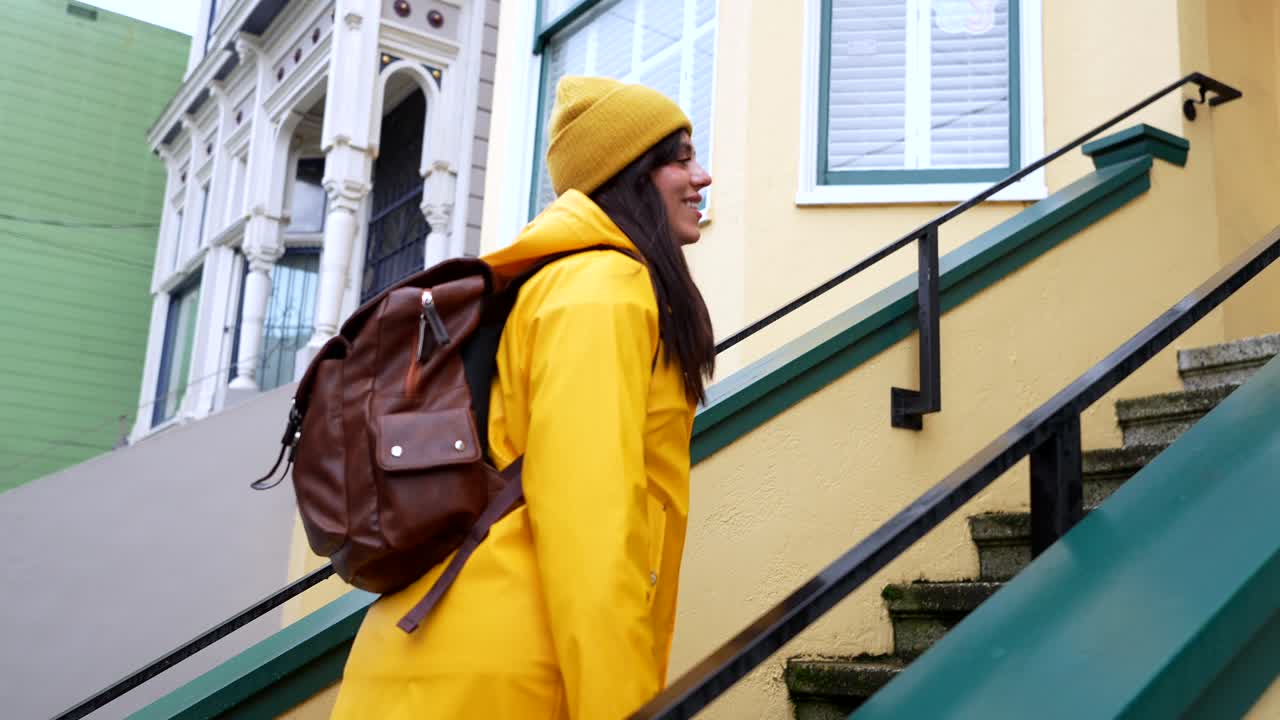 Young Woman in Yellow Raincoat Walking Up Residential Stairs