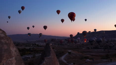 aerial dolly in shot as hot air balloons launch over goreme cappadocia at sunrise