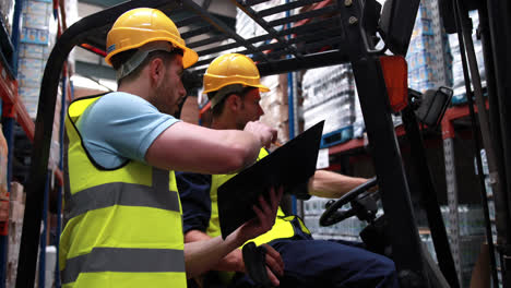 Warehouse-worker-talking-with-forklift-driver-