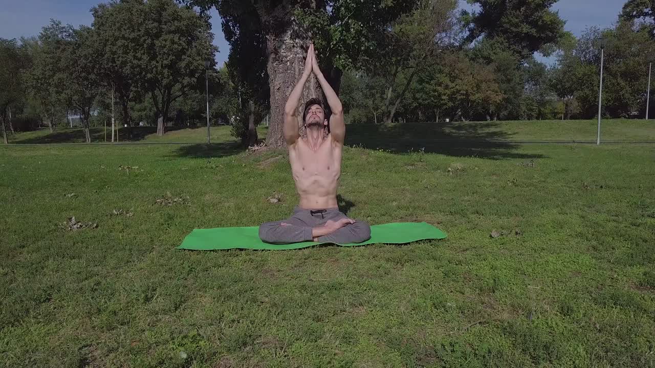 joven hombre caucásico practica yoga matutino y estiramiento en el parque