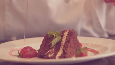 chefkoch gießt sirup über ein schokoladen-dessert