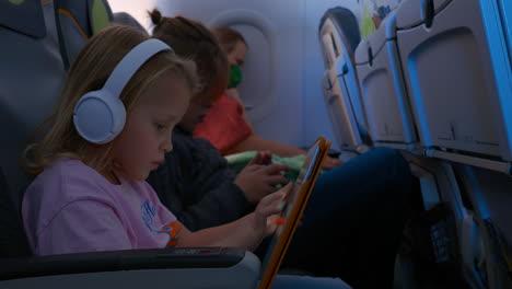 children with gadgets and sleeping mother in the plane