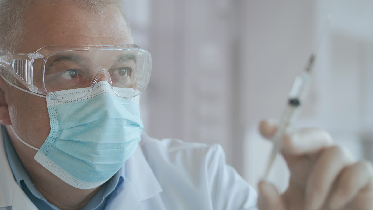 las manos del médico preparando una jeringa con antibiótico para el tratamiento intravenoso. una jeringa con un medicamento con una vacuna está en las manos de un médico el medicamento se exprime fuera de la jeringa cae. imágenes de alta calidad 4k