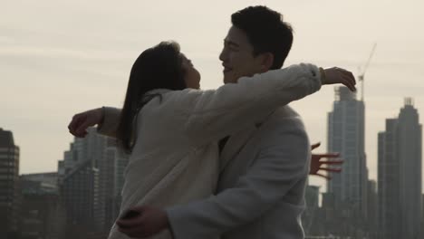 Young-Asian-Couple-With-Romantic-Man-Proposing-To-Woman-Against-City-Skyline