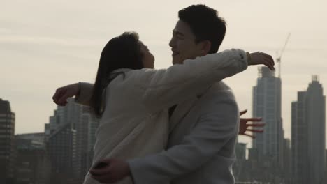 도시 스카이라인을 배경으로 여자에게 청혼하는 로맨틱한 남자와 젊은 아시아 커플