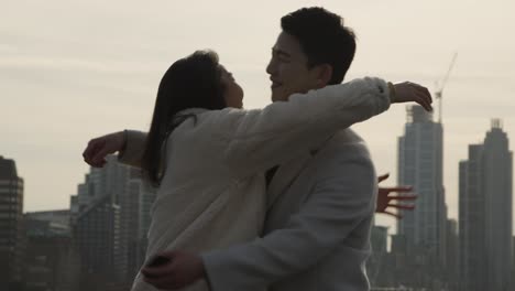 young asian couple with romantic man proposing to woman against city skyline