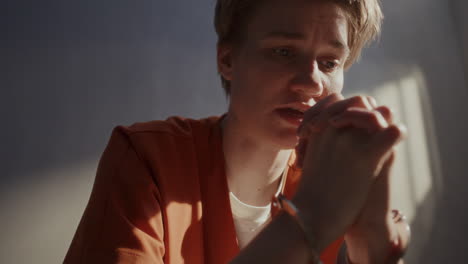 female inmate in handcuffs praying to god with hands clasped