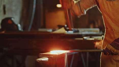 blacksmith striking hot steel billet on anvil with hammer