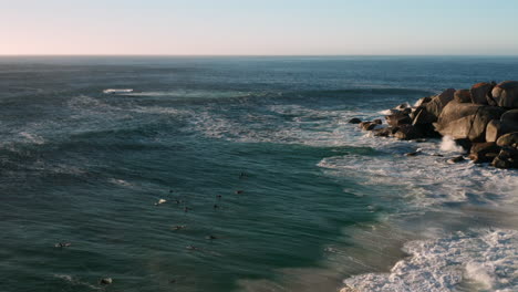 Aerial-of-Llandudno-where-surfers-trying-to-catch-a-wave-with-sunset-in-Cape-Town