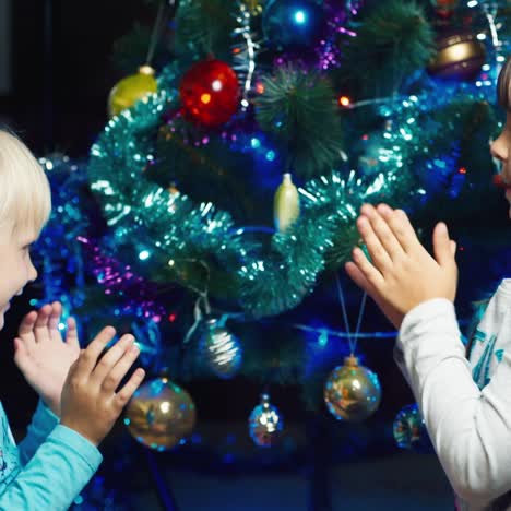 dos niños juegan bajo el árbol de navidad