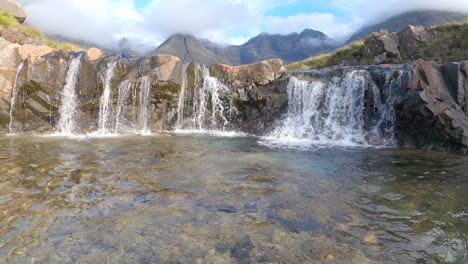 Wild-mountain-stream-running-through-wide-waterfall