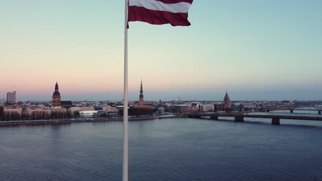 latvia flag wave with majestic city of riga in background, aerial view