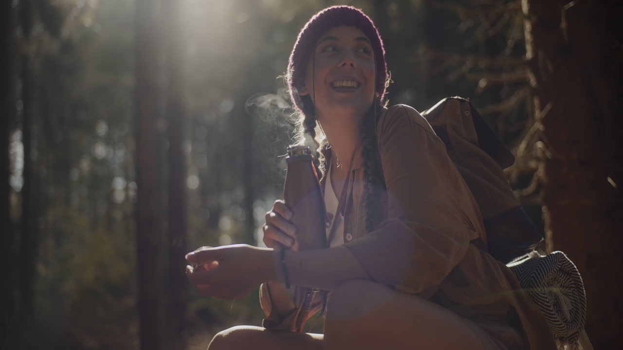 숲 에 앉아 있는 여자 가 병  ⁇ 개 를 열고 있다