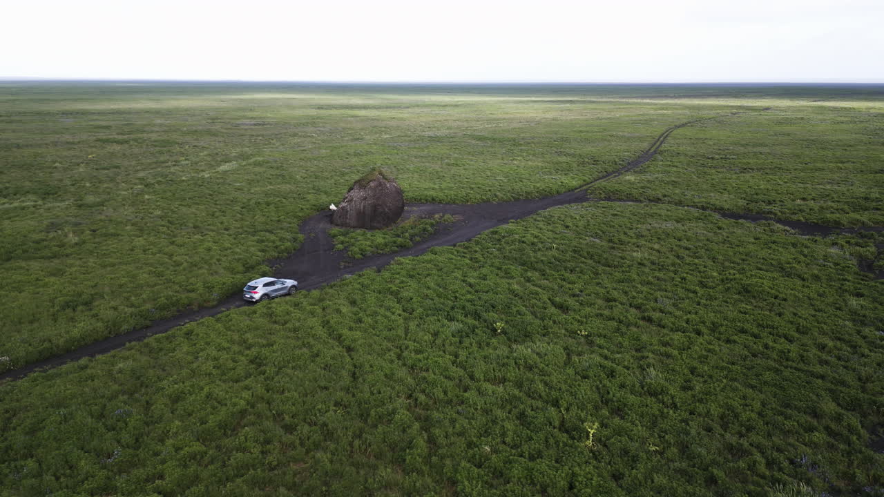 Lonely car on grassy Icelandic plain with distant horizon. Serenity