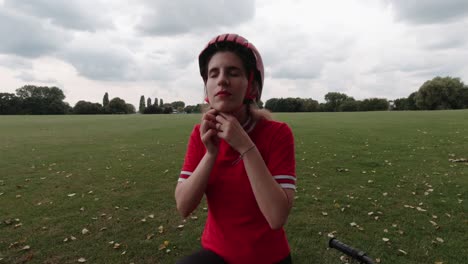 una joven ciclista caucásica se pone un casco rojo