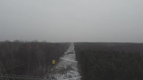 Drone-video-of-power-line-on-a-cloudy-day-in-forest-with-snow