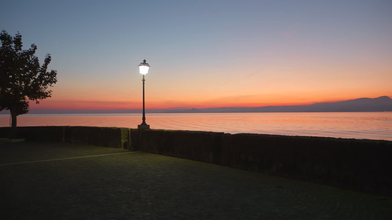 A beautiful sunset over Lake Garda, Italy, with calm water and a serene atmosphere.