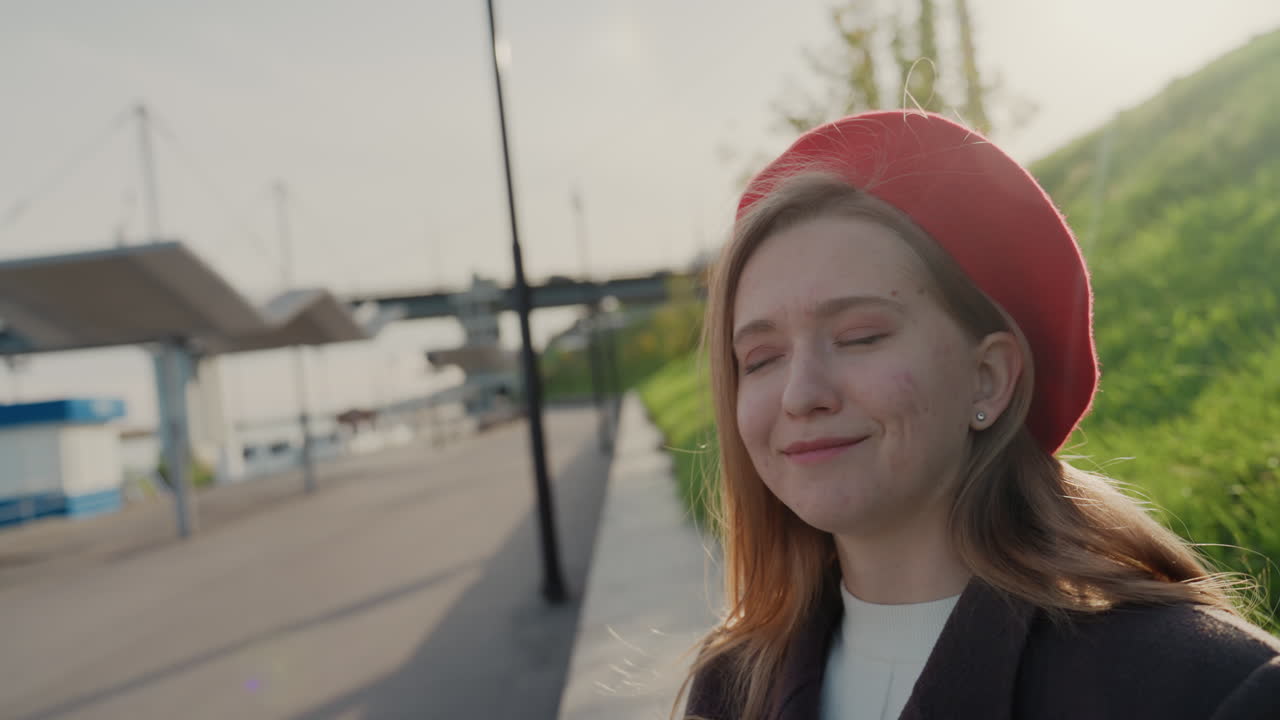 Hvid kvinde tjekker ur ved vandet, pendler kaster et legesygt irriteret blik på håndleddet, byplatform og havn i baggrunden, casual frakke og baret, rejsetid og hverdagsskema