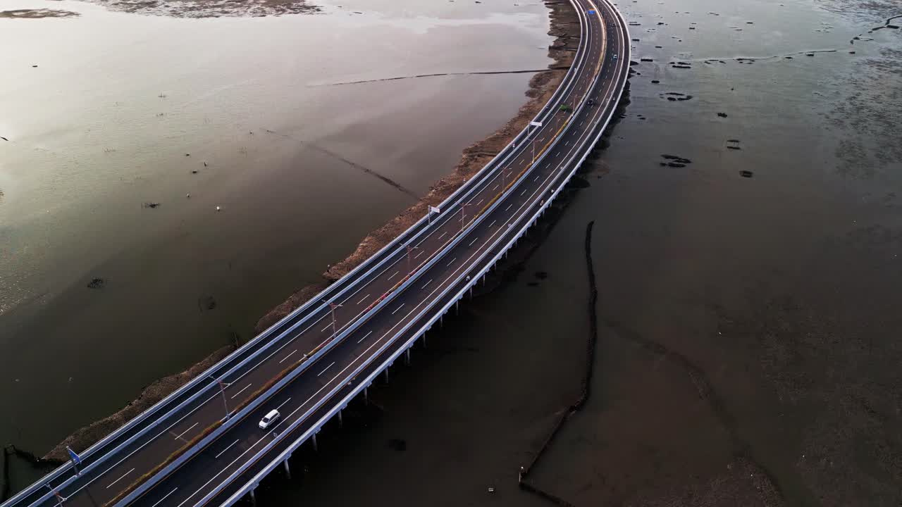 Bali Mandara Toll road bridge is filmed from drone flying high over tidal mud at low tide the tropical coastal view combines natural mudflats with modern island connection highway