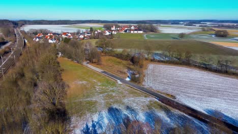 Eisenbahnstrecke-Durch-Verschneite-Landschaft-Und-Dorf