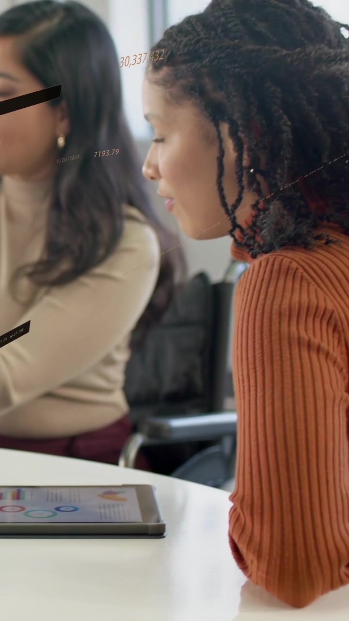 Video verticale: Donna con maglione color ruggine che parla in una riunione di lavoro, tocca un tablet e appaiono delle sovrapposizioni.