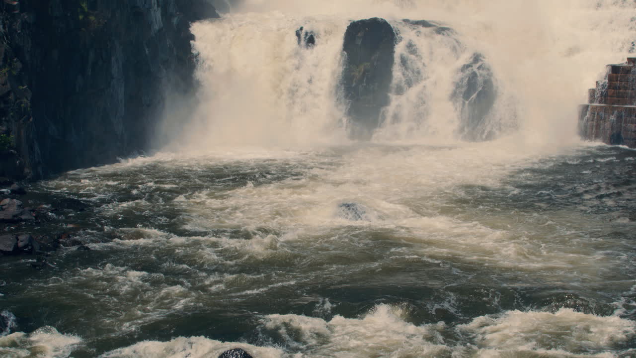 medium shot of bottom of new croton dam with powerful waterfall and stepped spillway leading down to the river. static, slow motion 40 fps