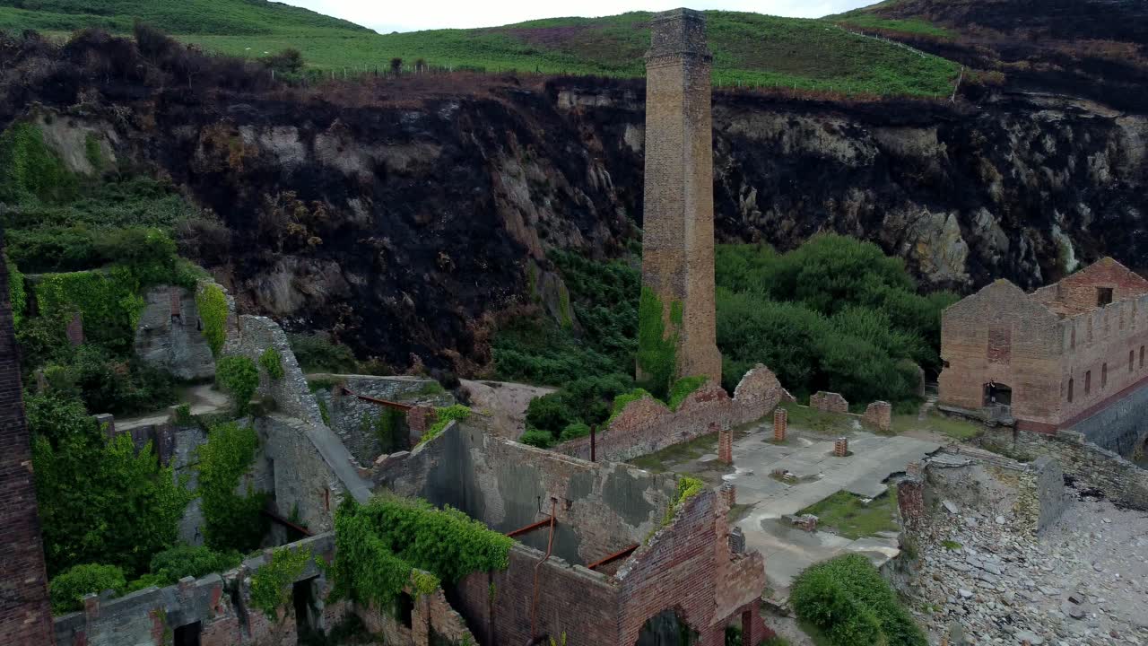 Cinematic aerial revealing tilt-up shot of the remains of the Porth Wen Brickworks in Anglesey, North Wales, Europe