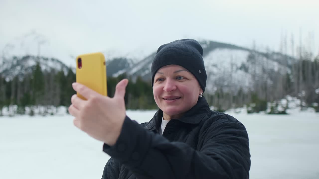 Kvinne på videosamtale utendørs om vinteren
