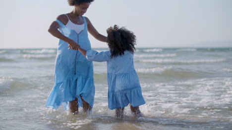 amorosa madre y su linda hija bailando juntas y divirtiéndose en el mar