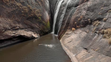 mesmerizing view of spectacular isolated and uninhabited waterfall, amidst the steep walls of the brown rocky mountain forming a pond