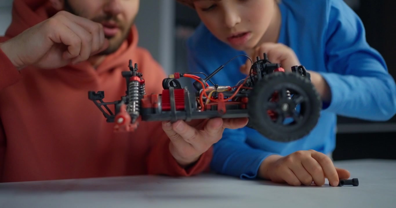 Padre e hijo ensamblando un coche teledirigido juntos.