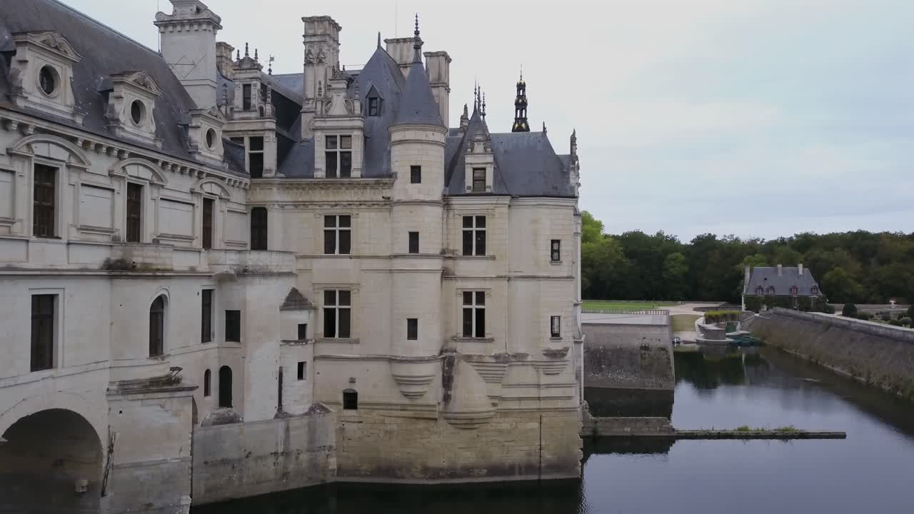 Drone shot revealing stunning Renaissance architecture of historic Chateau de Chenonceau and moat, with birds flying by, Loire Valley, France