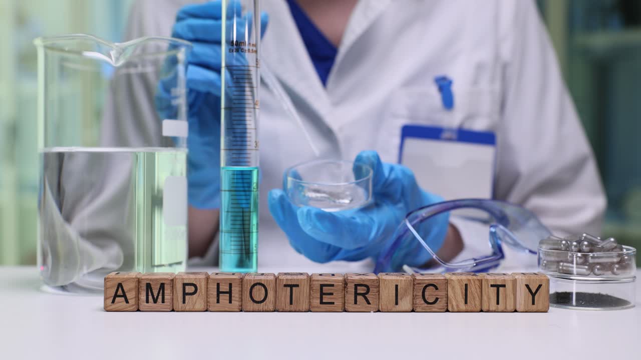 Wooden cubes spell word amphotericity on desk near glassware