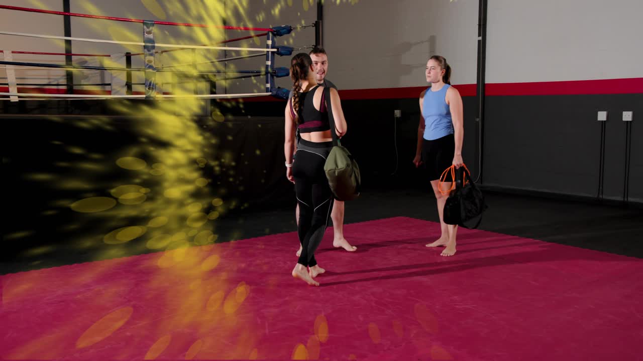 Women with bags, rope walking onto boxing mat to coach, yellow particles trailing, warming up