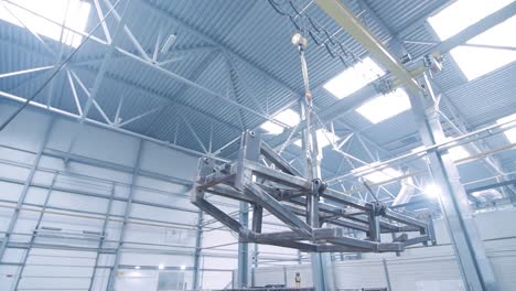 hook of crane with chains moving big metal carcass in workshop