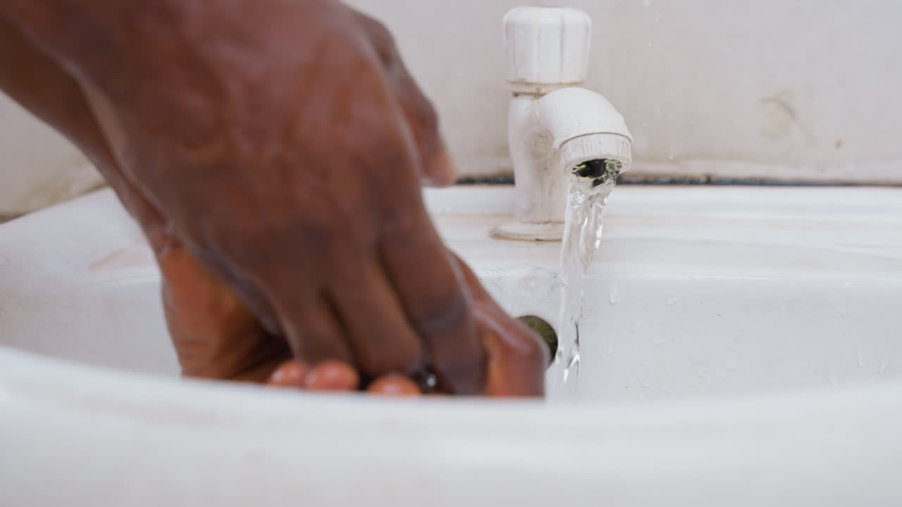 Soothing water cleanup after chores. Calm domestic scene with soft water flow and pink soap. Tranquil routine of rinsing hands in bathroom sink with gentle water and pink soap bottle