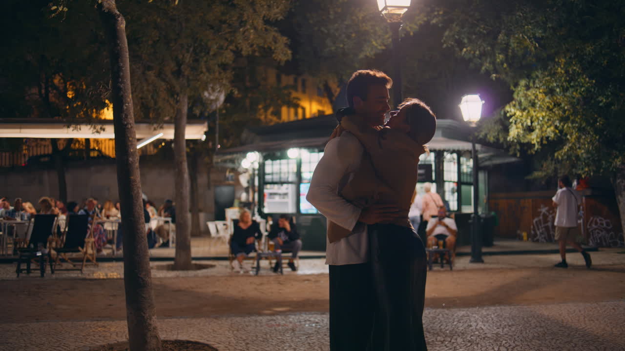 Happy man spinning woman on evening city street. Joyful couple dating at night