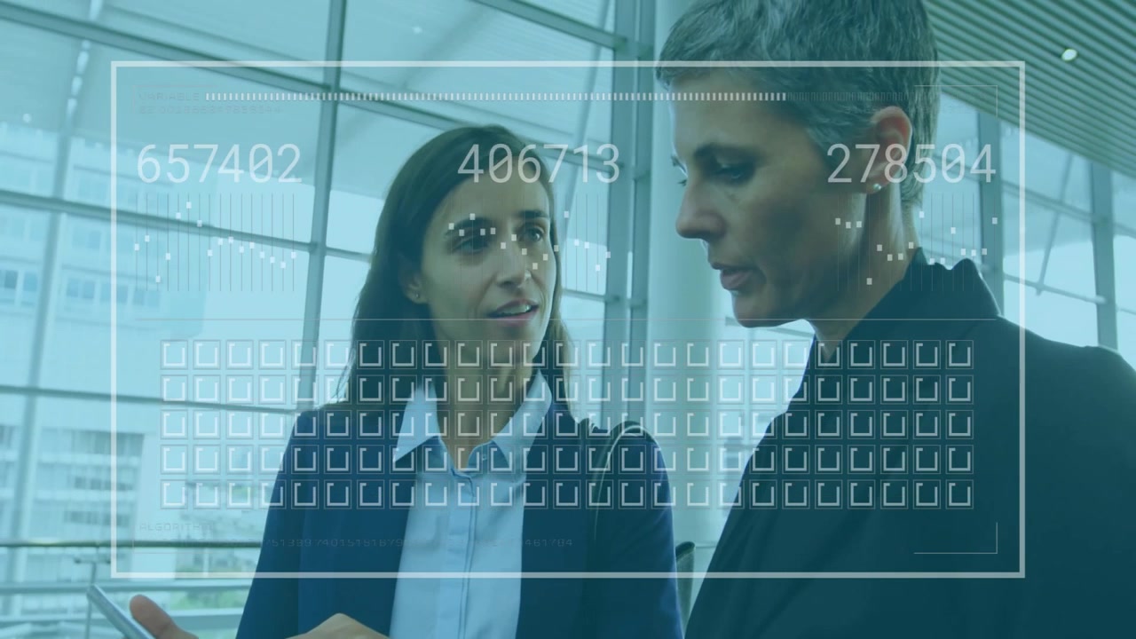 Donna d'affari che tocca lo smartphone mostrando una dashboard che aggiorna le metriche aziendali mentre un collega osserva