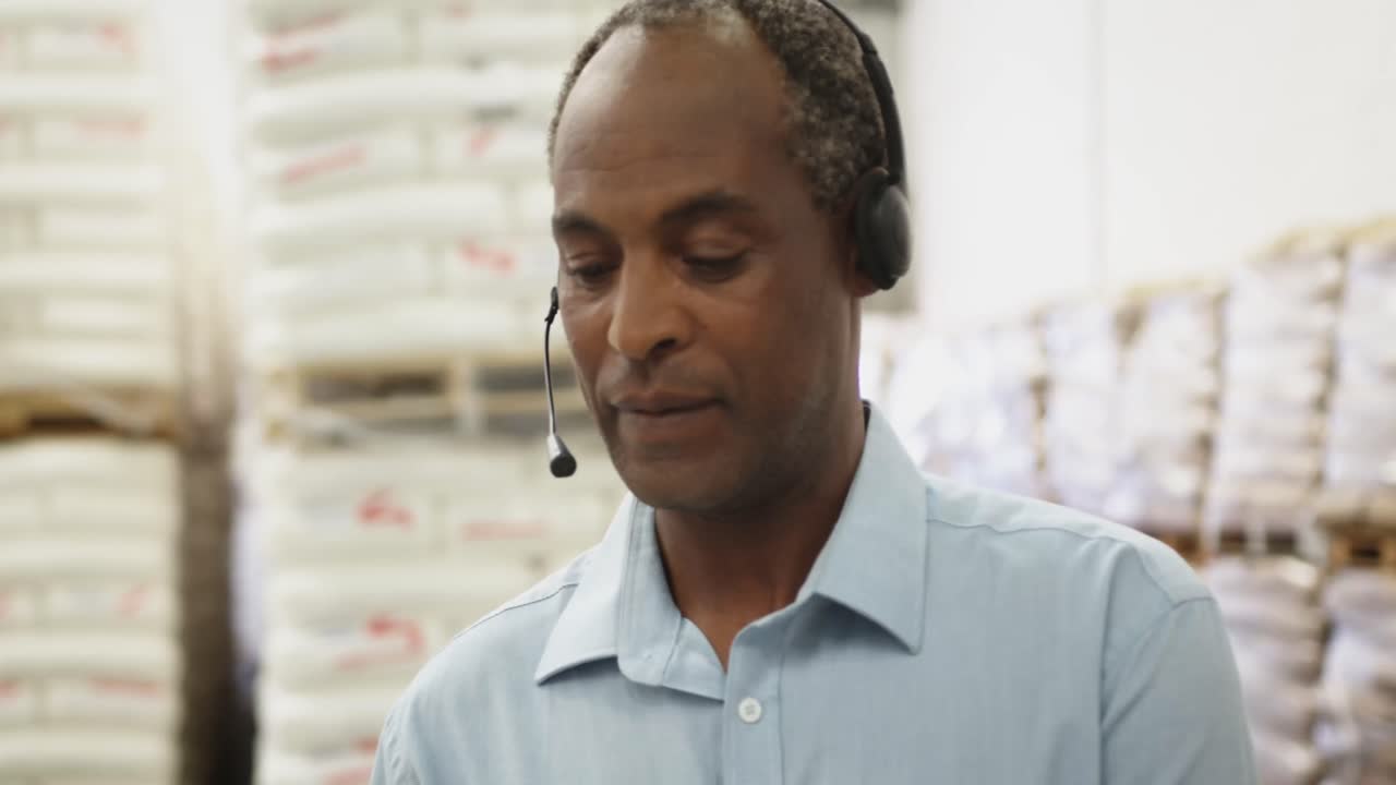 Portrait of middle aged man in warehouse storeroom wearing a headset 4k