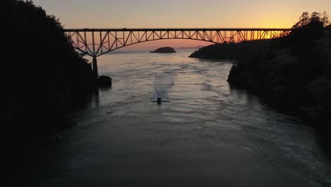aerial view of a motorboat traveling under deception pass at sunset on a warm summer evening