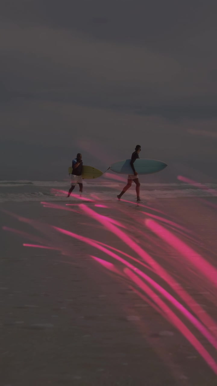 Video verticale: Due surfisti si preparano a fare surf, correndo con le tavole, con una scia rosa che li copre.